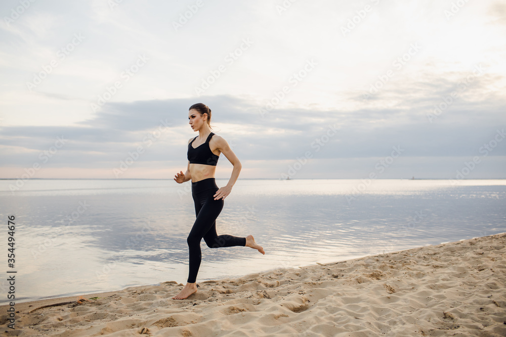 Beautiful athletic woman running along a beautiful sandy beach, healthy lifestyle, enjoying an active summer vacation by the sea