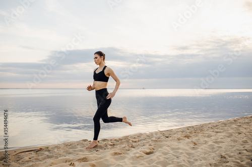 Beautiful athletic woman running along a beautiful sandy beach, healthy lifestyle, enjoying an active summer vacation by the sea