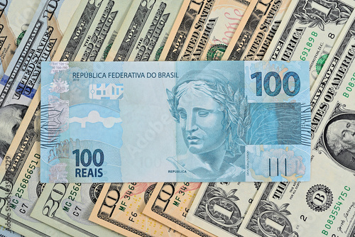 Nota de 100 reais junto com dólares americanos de diversos valores
