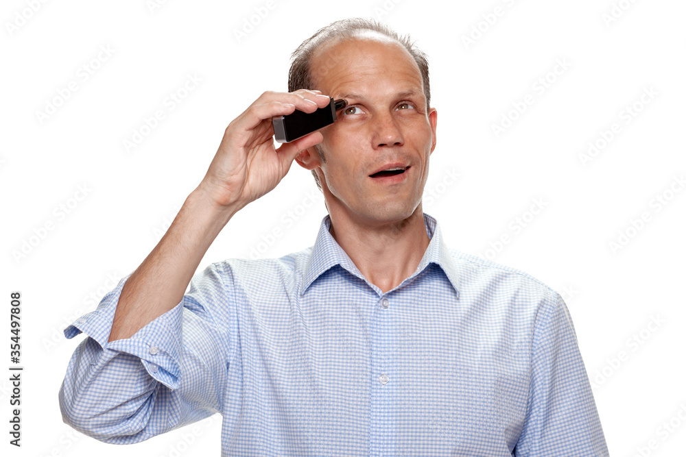 Portrait of young man removing hair from his eyebrow with electric trimmer Portrait of young man removing hair from his eyebrow with electric trimmer