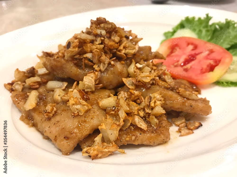 Fried pork with garlic serve with slice tomato and lettuce. Fried pork with garlic serve with slice tomato and lettuce.