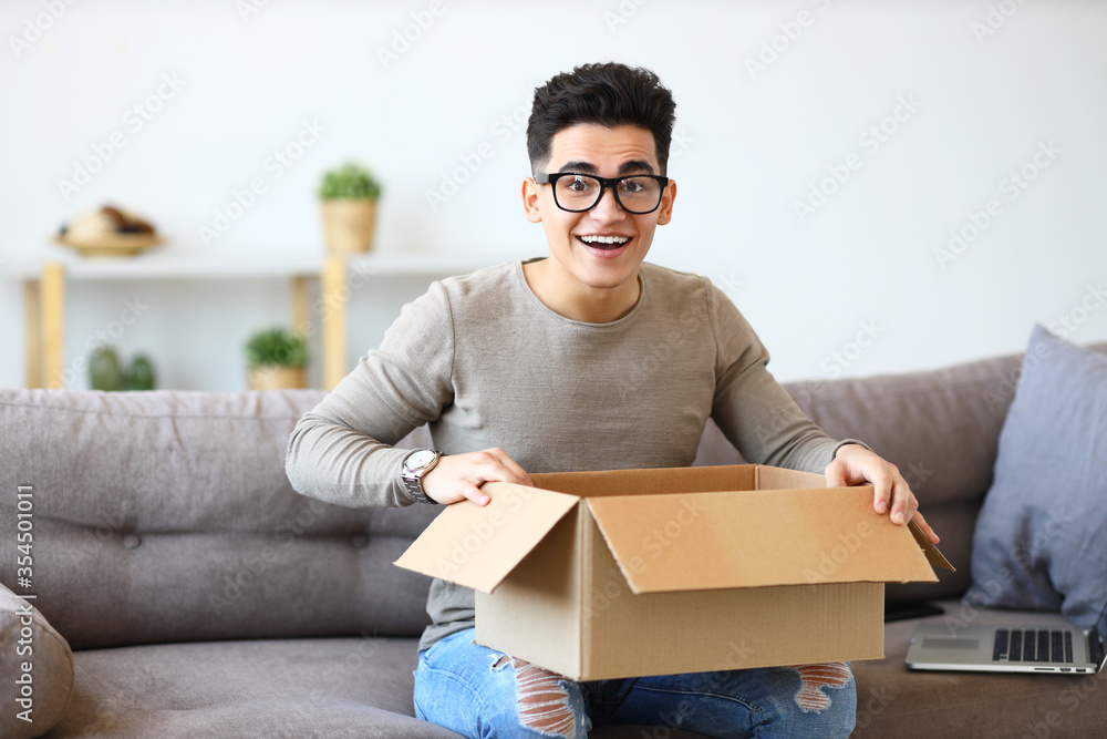 Happy man unpacking delivery box on sofa. Happy man unpacking delivery box on sofa.