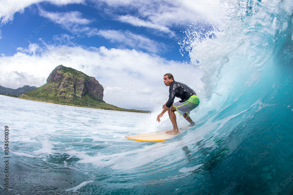 Surfing on big waves against the backdrop of picturesque mountains and beautiful clouds