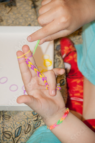 Сhild making a rubber loom bracelet with a hook.Children hands photo