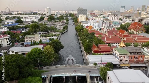 Boats moving to station for embarkation and disembarkation. Boats moving pass under the bridge. There are views along the canal ex. temple, walk way. photo