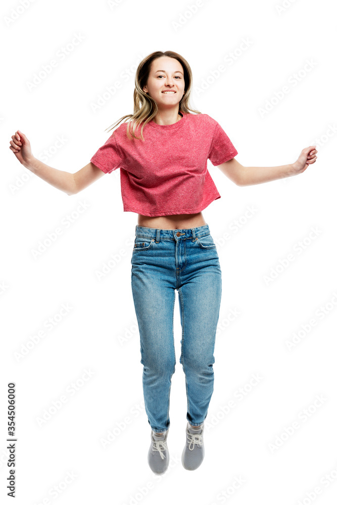 Young laughing jumping girl in a red tank top and jeans. Happy time. Isolated on a white background. Vertical. Young laughing jumping girl in a red tank top and jeans. Happy time. Isolated on a white background. Vertical.