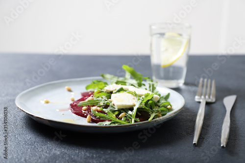 Plate with arugula  beet and feta salad. Sprinkled with pine nuts and honey