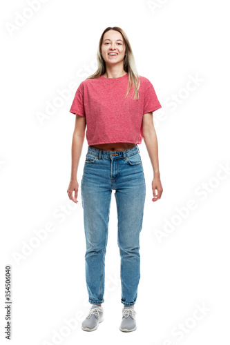 Smiling young girl in a red tank top and jeans. Full height. Isolated on a white background. Vertical.
