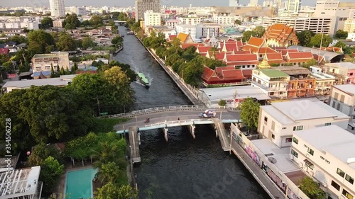 Boats moving to station for embarkation and disembarkation. Boats moving pass under the bridge. There are views along the canal ex. temple, walk way. photo