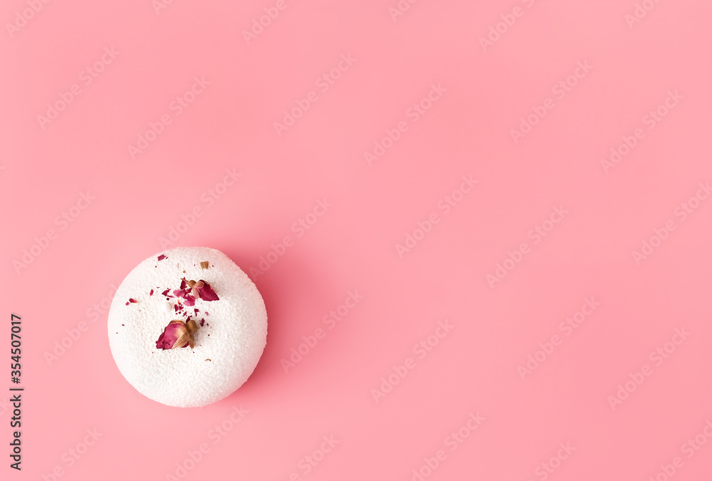 One mousse pastry dessert covered with white chocolate and decorated with rose buds on pastel pink background. Modern stylish cake. Flat lay style. Copy space. Close-up.