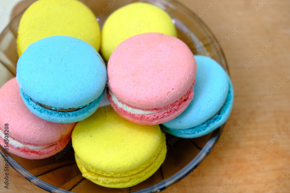 Colorful french Sweet Pastries Macaroons on glass plate on a wooden tray isolated on white background. Colorful french Sweet Pastries Macaroons on glass plate on a wooden tray isolated on white background.