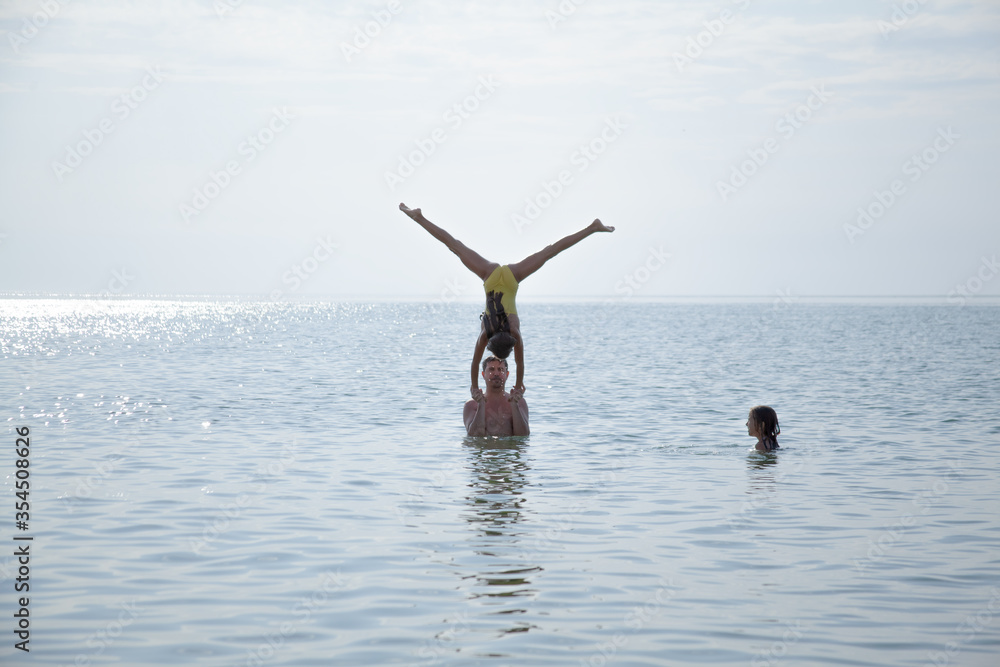 Father take fun with his daughters. The kids do acrobat element in water on the water Father take fun with his daughters. The kids do acrobat element in water on the water