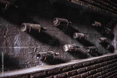Old, ancient wine collection and dusty wine bottles in an underground cellar Dark key shooting, selective focus © Irina