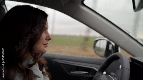 Brunette woman driver behind the steering wheel driving her crossover suv car photo