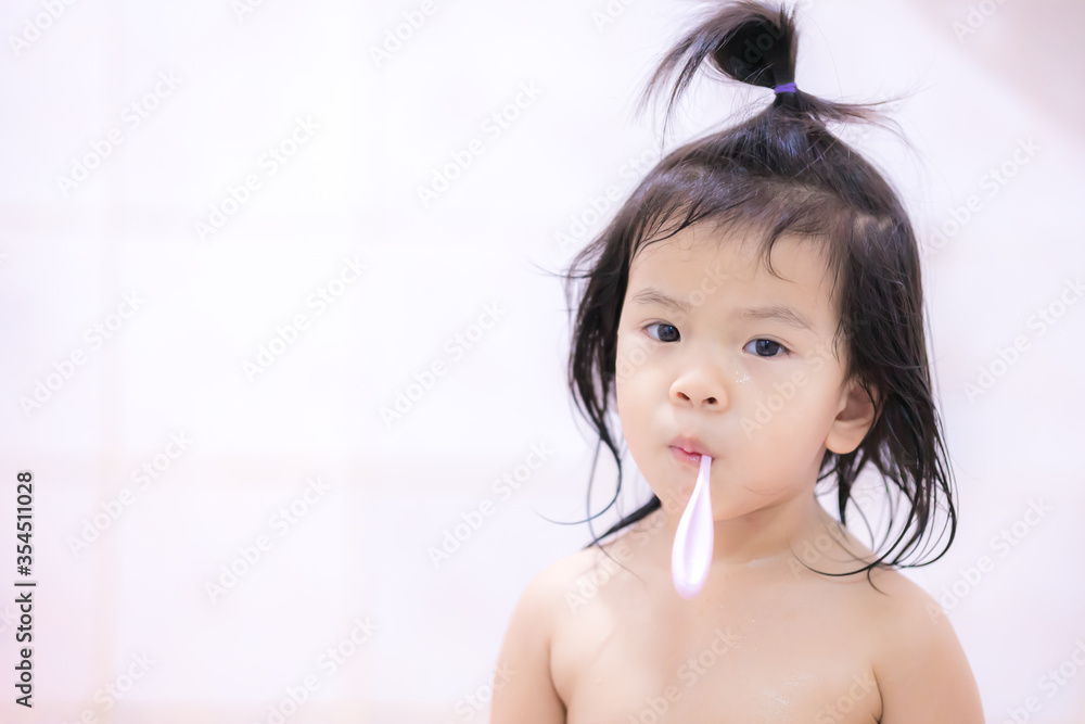 Adorable Asian girl is standing, taking a shower and brushing her teeth