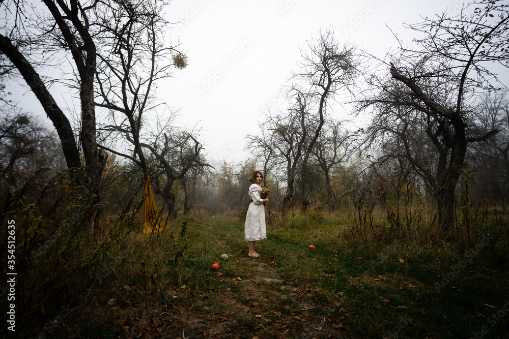 Lonely woman surrounded by fruit trees stands barefoot on the cold grass Lonely woman surrounded by fruit trees stands barefoot on the cold grass