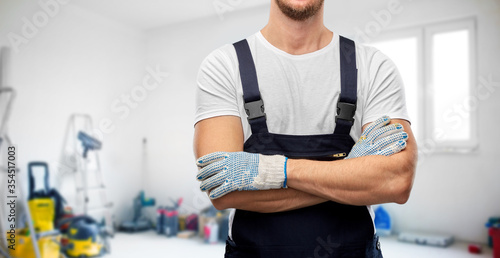 Fototapeta Naklejka Na Ścianę i Meble -  repair, construction and building - close up of male painter or builder in overall and gloves over utility room background
