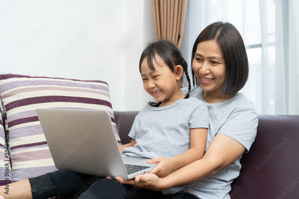 Asian mother and daughter using laptop studying homework online lesson at home, Social distance online education idea concept Asian mother and daughter using laptop studying homework online lesson at home, Social distance online education idea concept