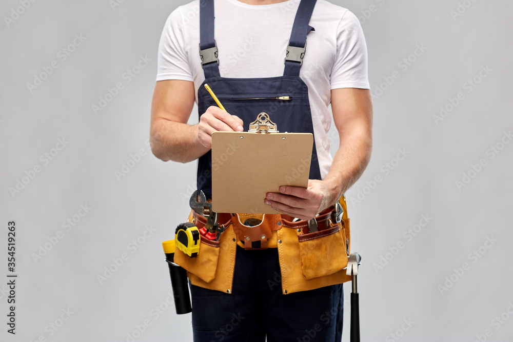 repair, construction and building - male worker or builder with clipboard, pencil and working tools on belt over grey background repair, construction and building - male worker or builder with clipboard, pencil and working tools on belt over grey background