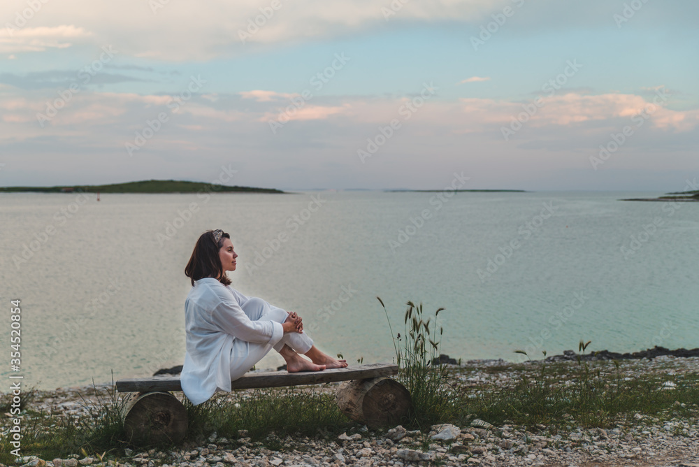 woman sitting on bench looking on sunset over the sea