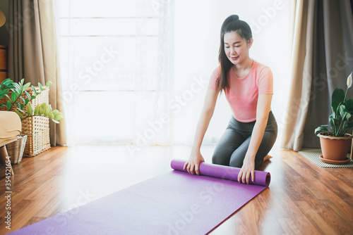 Beautiful attractive young asian woman wearing sportswear practicing yoga mats at home in the living room in the morning. Sport and recreation concept. 