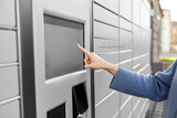 mail delivery and post service concept - close up of woman's hand choosing operation on outdoor automated parcel machine's touch screen