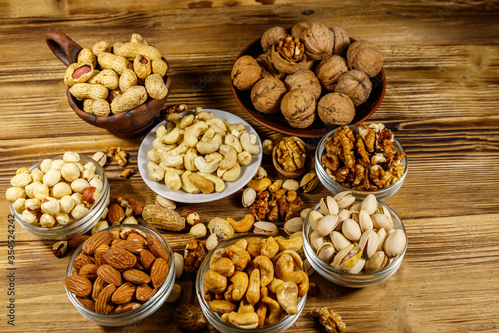 Assortment of nuts on wooden table. Almond, hazelnut, pistachio, peanut, walnut and cashew in small bowls. Healthy eating concept Assortment of nuts on wooden table. Almond, hazelnut, pistachio, peanut, walnut and cashew in small bowls. Healthy eating concept