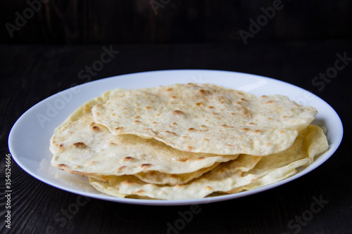 Delicious pita bread made at home in a pan. Thin pita bread on a white plate © Olga