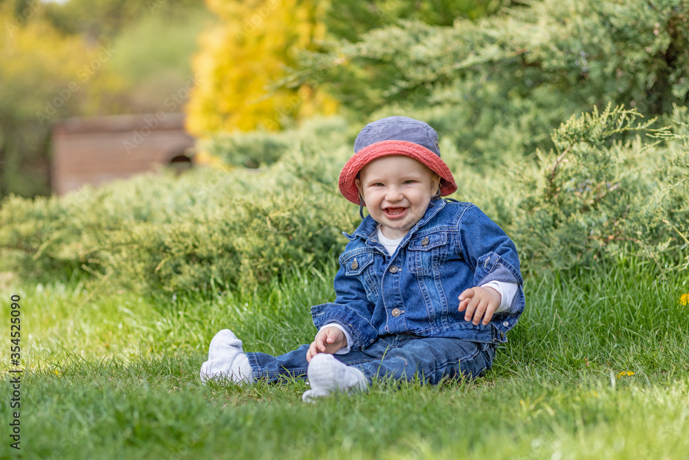 Laughing cute little baby boy is sitting outdoors and looking at the camera Laughing cute little baby boy is sitting outdoors and looking at the camera