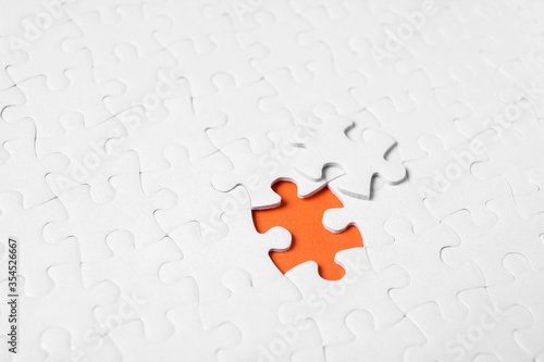 Blank white puzzle with separated piece on orange background