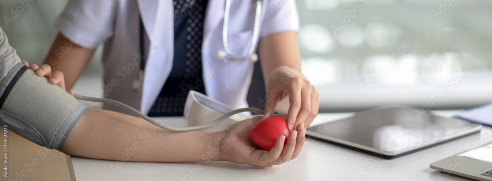 Fototapeta premium Close up view of young female doctor measuring blood pressure of patient