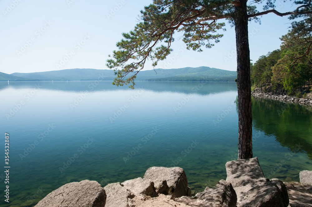 Turgoyak lake with pine tree in the foreground and mountains in the background, South Urals, Russia Turgoyak lake with pine tree in the foreground and mountains in the background, South Urals, Russia