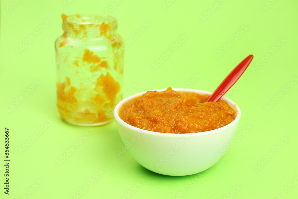 pumpkin porridge in a bowl with a spoon on a green background and an empty glass jar, baby or vegan food pumpkin porridge in a bowl with a spoon on a green background and an empty glass jar, baby or vegan food