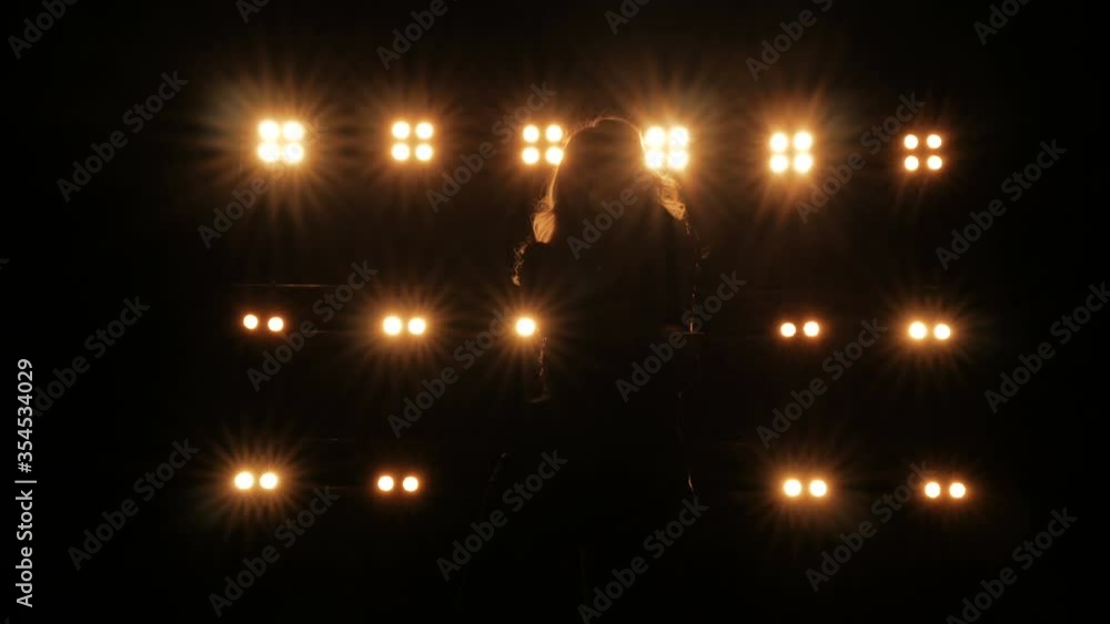 Silhouette of a girl dancing on the background of bright lights on the stage of a night club Silhouette of a girl dancing on the background of bright lights on the stage of a night club
