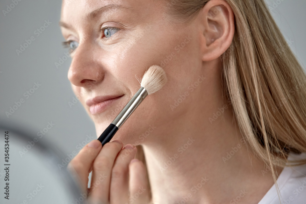 A large face of a young girl who puts a cosmetic brush on her face. A large face of a young girl who puts a cosmetic brush on her face.