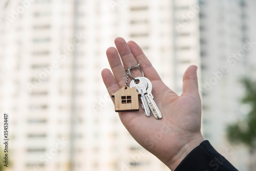 Buying a house, building repair and mortgage concept. Estimation real estate property with loan money and banking. Keys in hands on building background.  photo