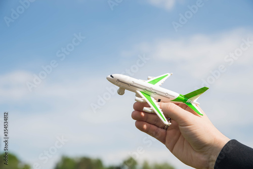 Plane in blue sky. Airplane flight permit. Man holding toy aircraft in hand. Air travel concept.