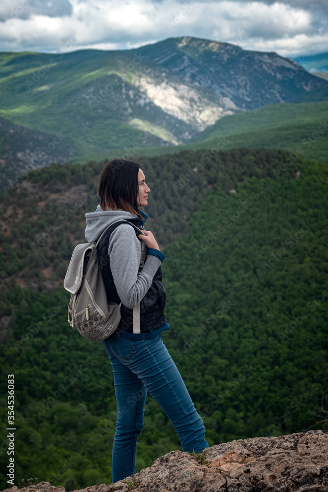 Young traveling woman on the top of the mountain cliff