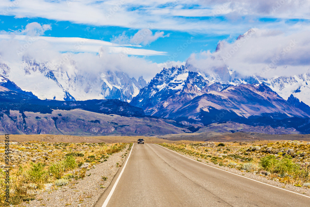 Fototapeta premium Car on the beautiful road of Patagonia, Argentina. Mountain range on the background Cerro Torre, mountains of the Southern Patagonian Ice Field in South America