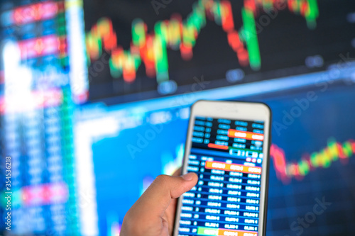 Blurred background of Monitoring investment stock or money exchange on smartphone in hand.Saving, Investment money concept.Growing up business and future.