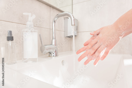 Closeup photo lady wash arms sink hot water rub soap bubbles between fingers for thirty seconds corona virus prevention sanitation concept responsible useful habit bathroom indoors