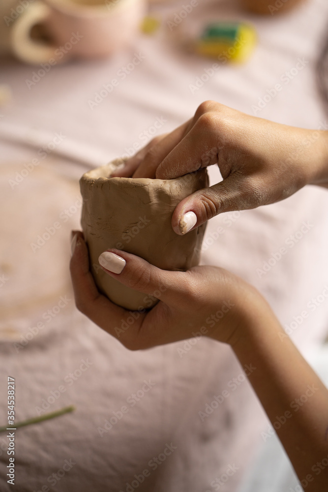 The potter's woman hands are shaped a cup from a clay. The process of creating pottery. The master ceramist works in his studio. Close-up, only hands. Crockery from clay own hands. The potter's woman hands are shaped a cup from a clay. The process of creating pottery. The master ceramist works in his studio. Close-up, only hands. Crockery from clay own hands.