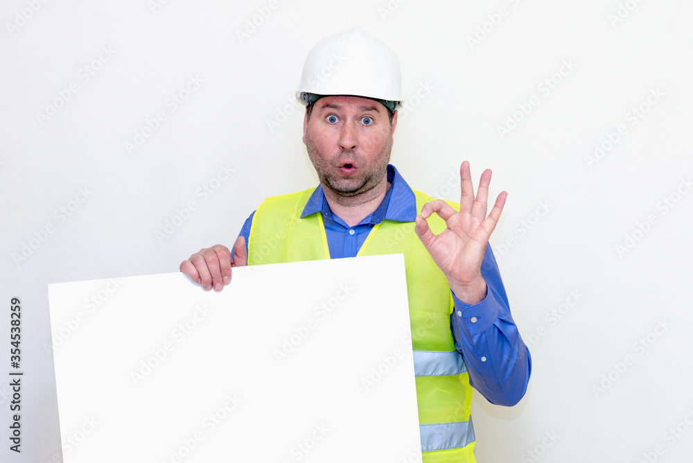 Close-up Engineer man wearing a helmet and reflector vest, standing and holding a billboard.Worker shows gesture ok. White background.