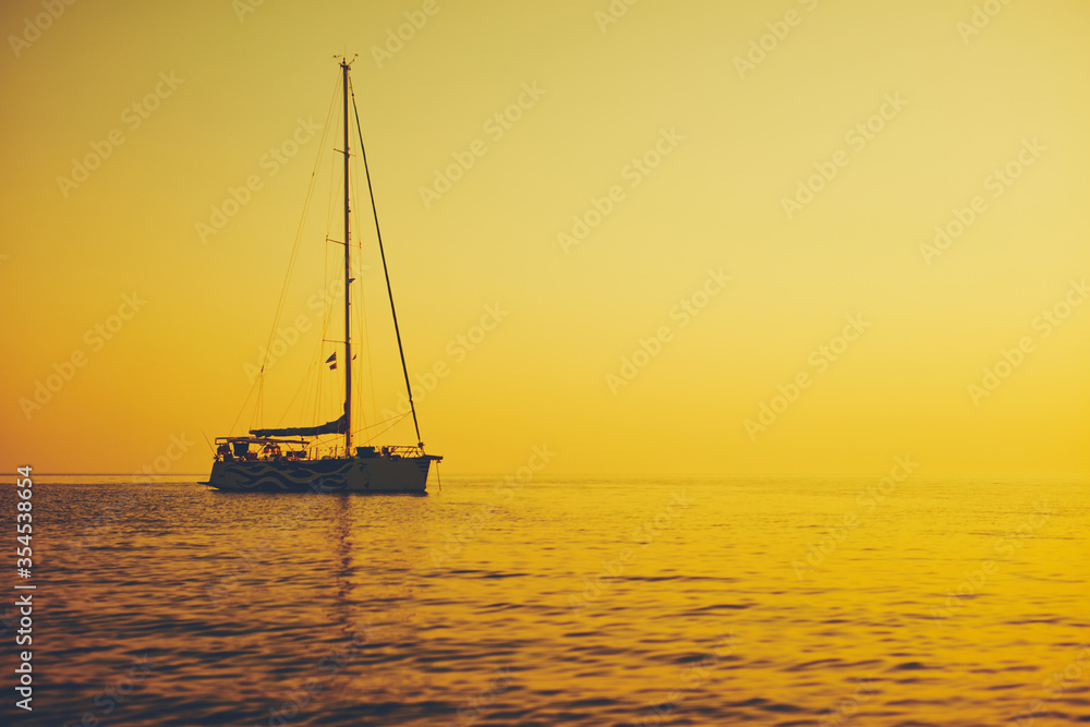 Silhouette of a sailing boat in sunset / sunrise time and ocean horizon. Silhouette of a sailing boat in sunset / sunrise time and ocean horizon.