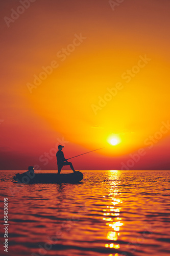 Silhouette of a fisherman fishing in sunset time on the open sea.