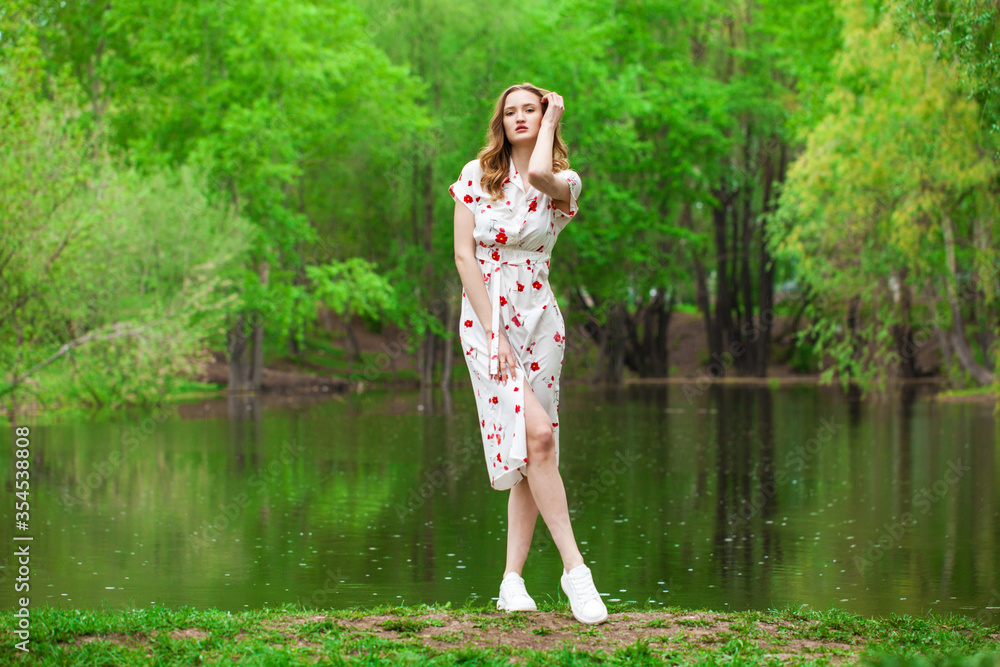 Portrait of a young beautiful woman in white dress posing by the lake Portrait of a young beautiful woman in white dress posing by the lake