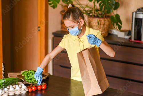 little girl with laptop. young woman holding blank sign. Coronavirus. Woman with face mask on quarantine, cooks in the kitchen at home during coronavirus crisis. Stay at home. Enjoy cooking at home. 