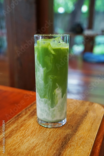 Close up glass of Iced Matcha green tea latte on wooden tray table