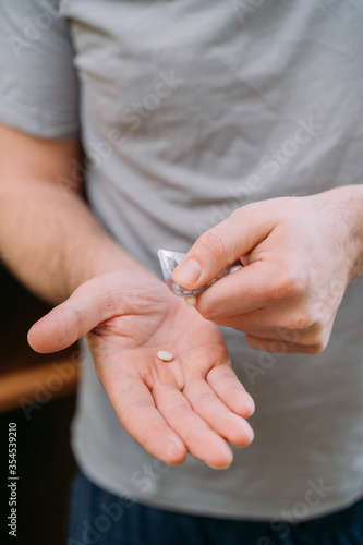 male hand squeezes pills out of packaging on palm 