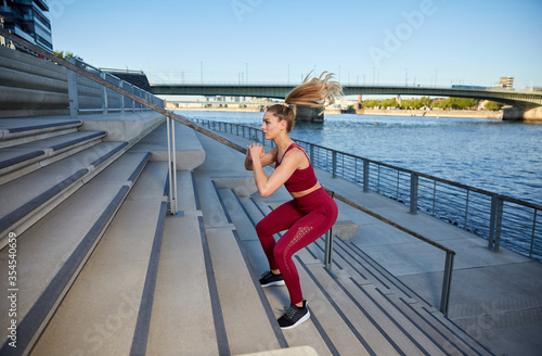 Young attractive woman makes High Intensity Intervall Training outdoor early morning in the city on a river